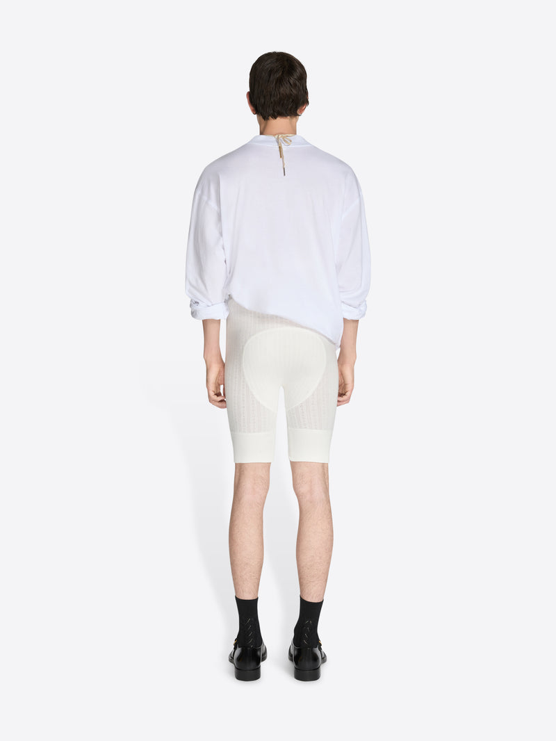 Person wearing a white shirt and cream-colored shorts on a white background - Dries Van Noten