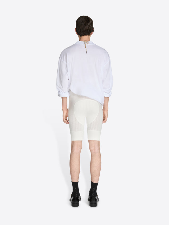 Person wearing a white shirt and cream-colored shorts on a white background - Dries Van Noten
