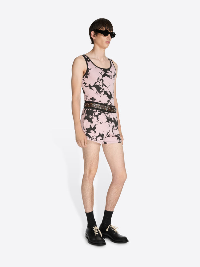 Person wearing a pink floral dress with black accents on a white background