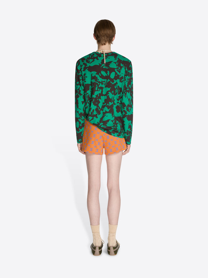 Person wearing a green camouflage hoodie and orange polka dot shorts on a white background