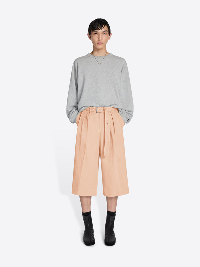 Person wearing a gray sweater and beige pants on a white background