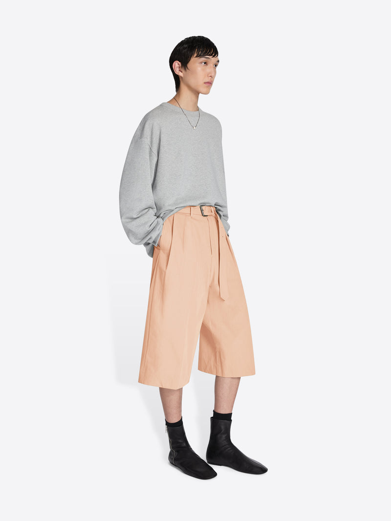 Person wearing a gray sweater and beige skirt on a white background