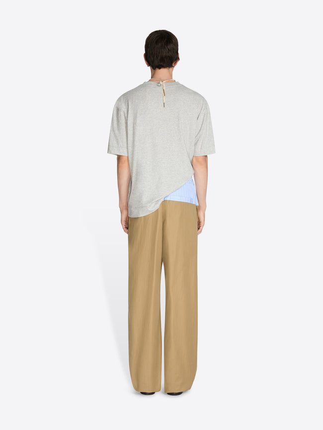 Person wearing a light-colored top and beige pants on a white background