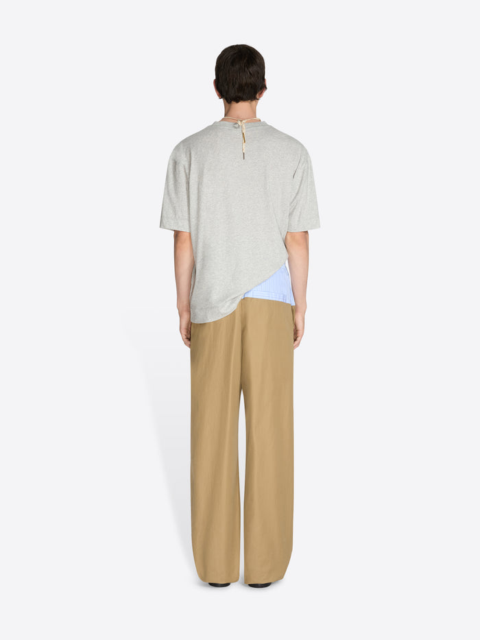 Person wearing a light-colored top and beige pants on a white background