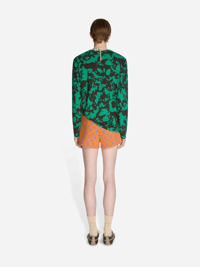 Person wearing a green camouflage hoodie and orange polka dot shorts on a white background