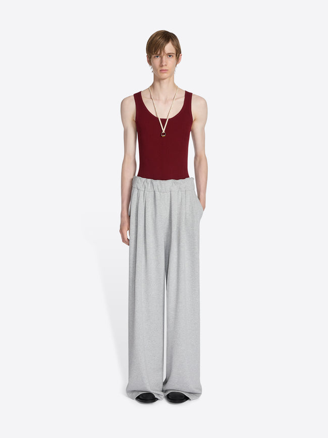 Person wearing a red tank top and gray wide-leg pants on a white background