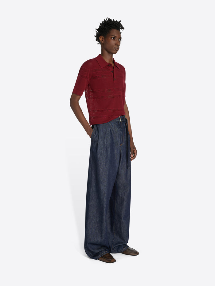 Person wearing a red polo shirt and dark blue wide-leg pants on a white background