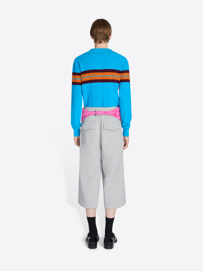 Person wearing a blue sweater with colorful stripes and gray pants on a white background - Dries Van Noten