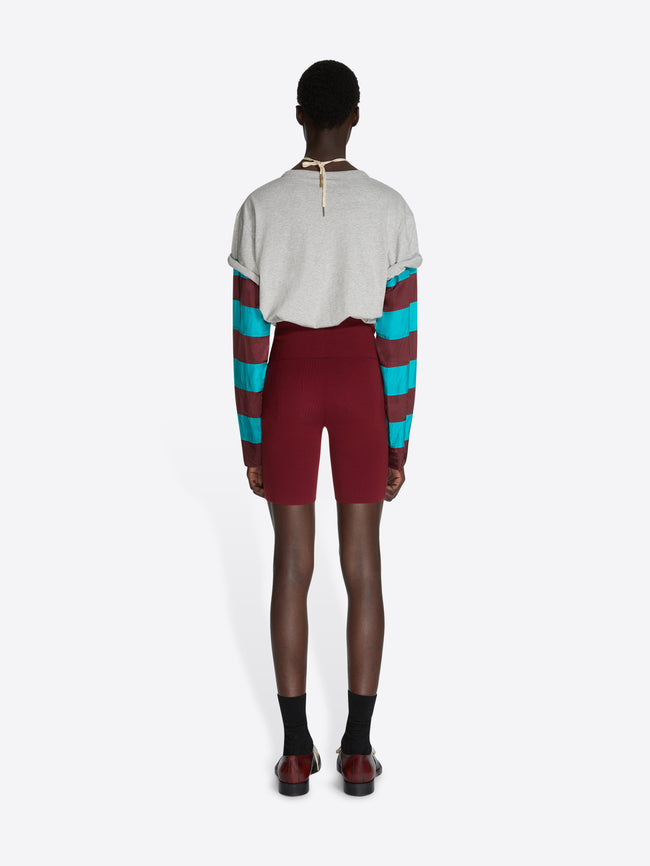 Person wearing a colorful striped sweater and maroon shorts on a white background