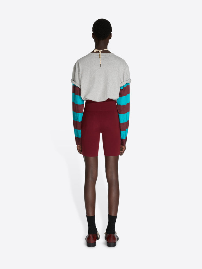 Person wearing a colorful striped sweater and maroon shorts on a white background