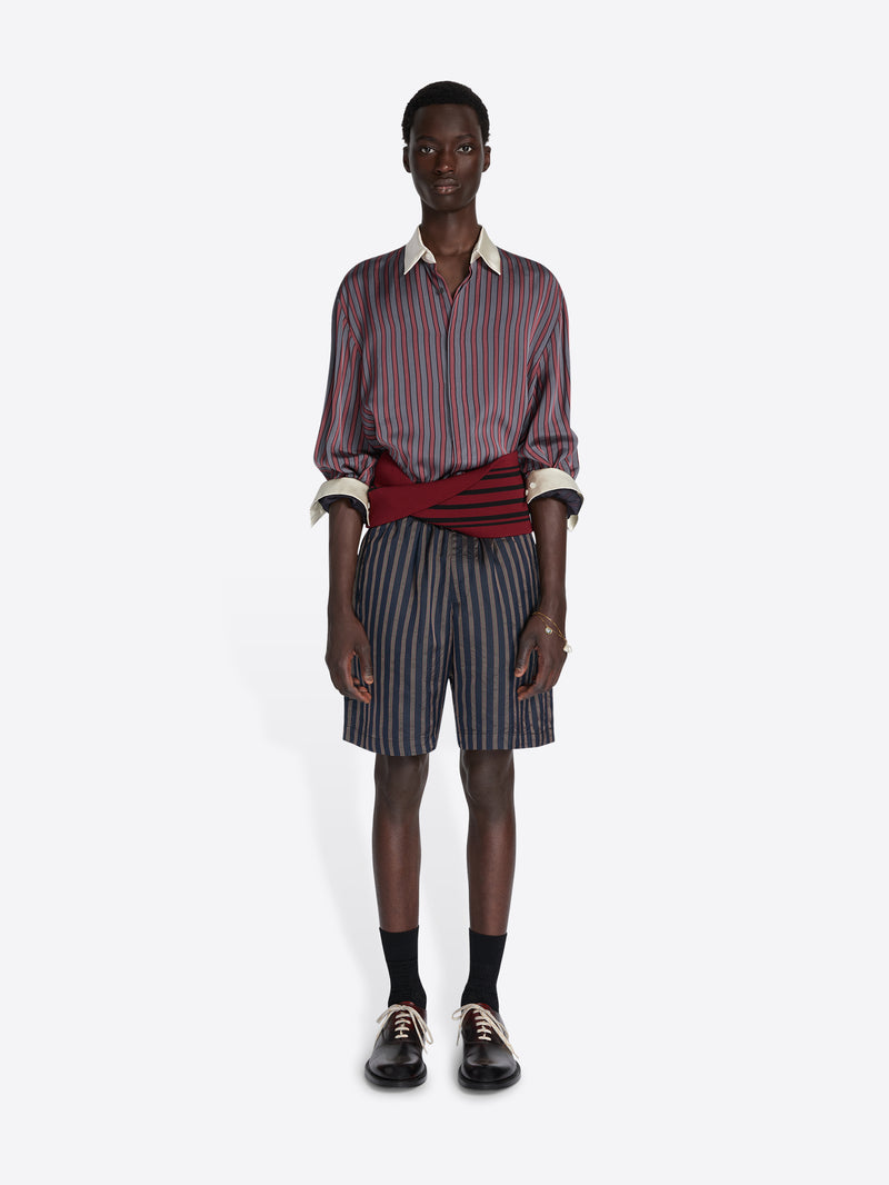 Man wearing a striped shirt and shorts on a white background