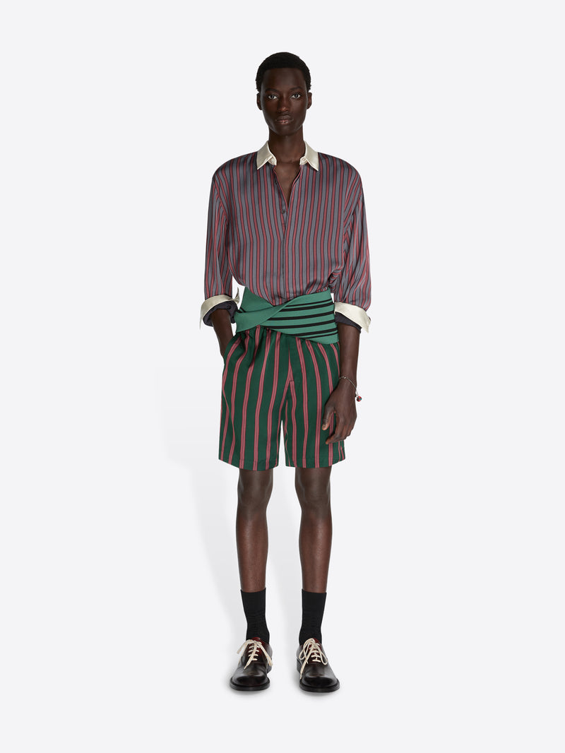 Person wearing a striped shirt and green and red striped shorts on a white background