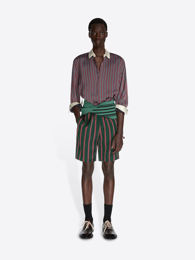 Person wearing a striped shirt and green and red striped shorts on a white background