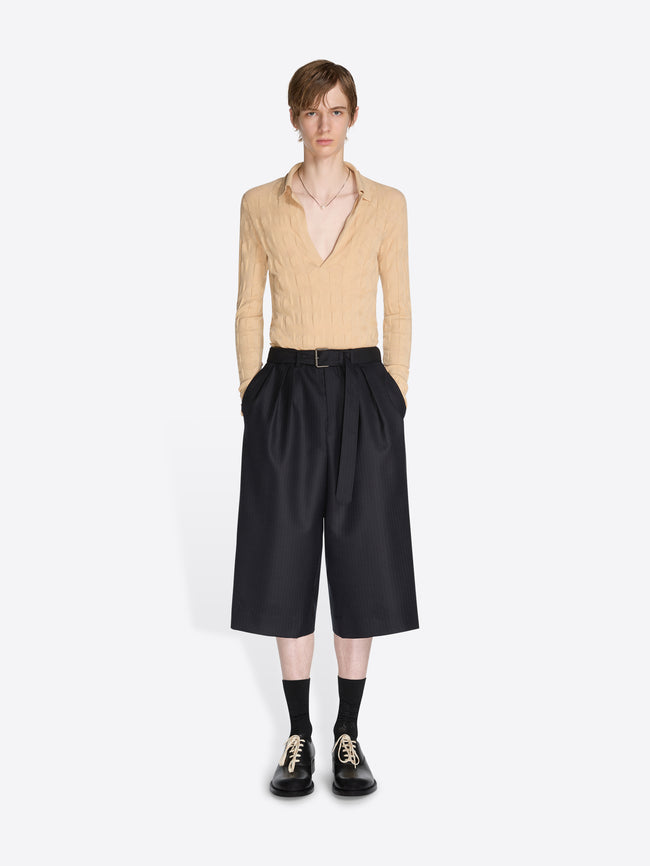 Person wearing a beige sweater and black pants on a white background - Dries Van Noten