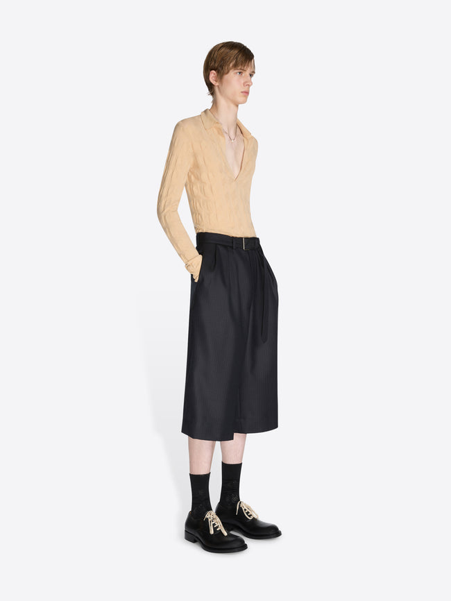 Person wearing a beige sweater and black skirt on a white background - Dries Van Noten