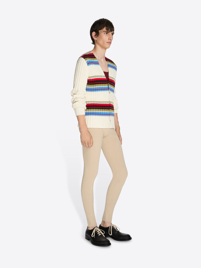 Person wearing a colorful striped sweater and beige pants on a white background