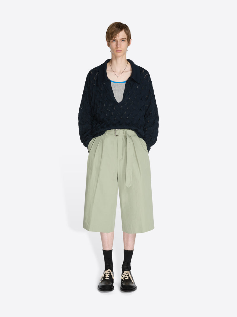 Person wearing a knit sweater and pants on a white background