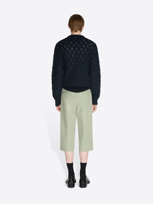 Person wearing a knit sweater and pants on a white background