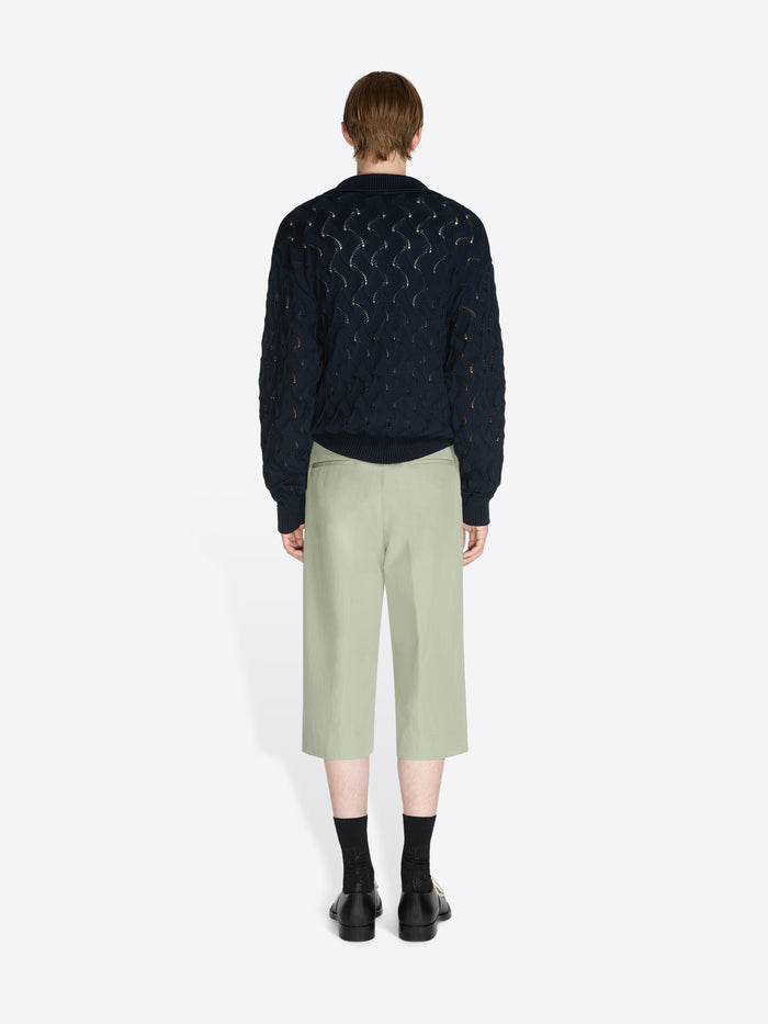 Person wearing a knit sweater and pants on a white background