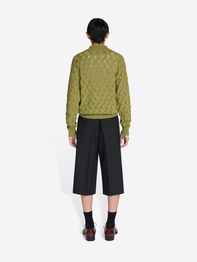 Person wearing a knit sweater and pants on a white background