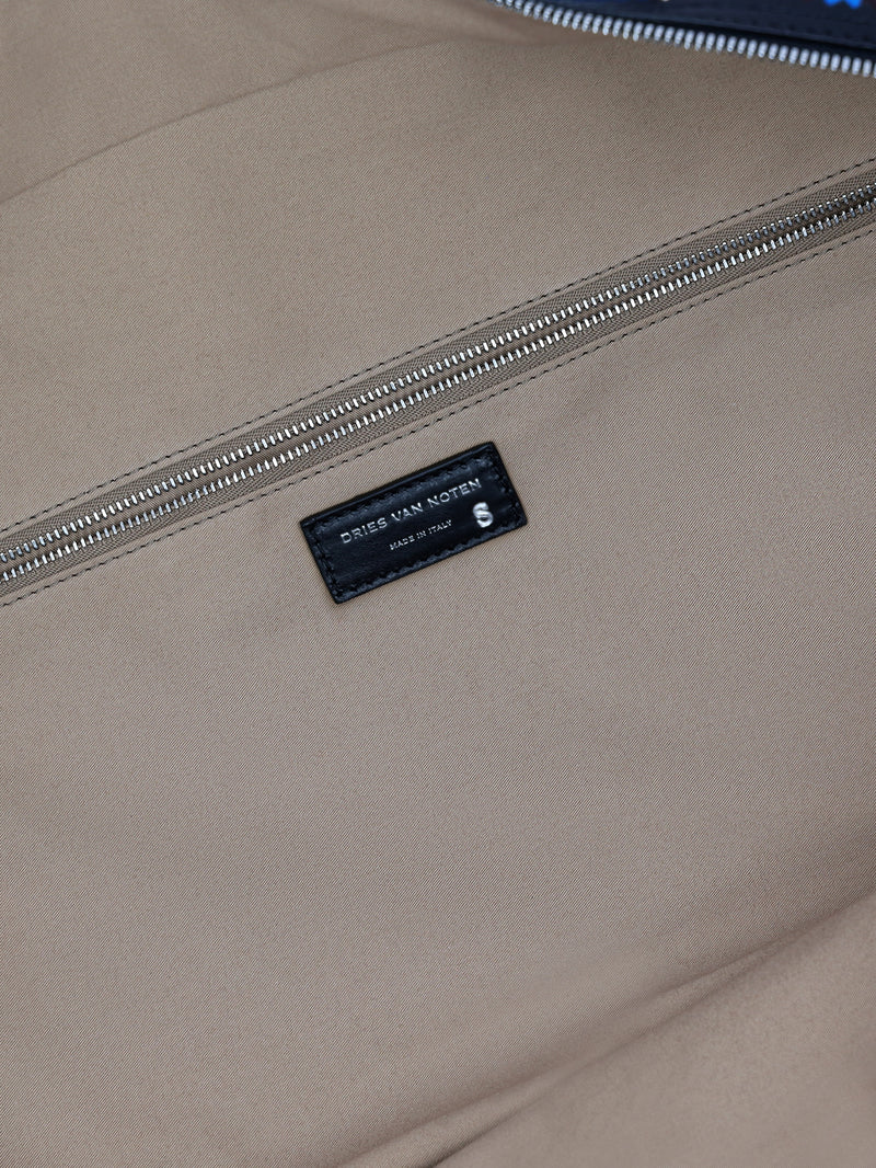 Close-up of a beige bag with a brand label on a blurred background - Dries Van Noten
