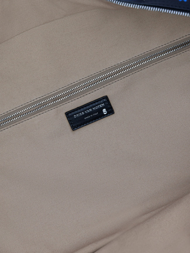 Close-up of a beige bag with a brand label on a blurred background - Dries Van Noten