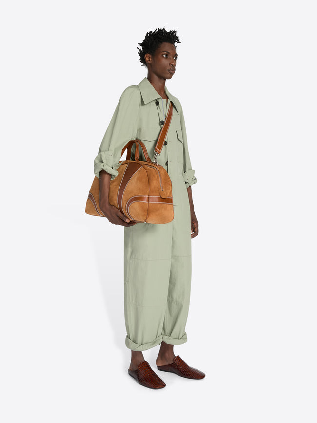 Person wearing a light green outfit with a brown leather bag on a white background - Dries Van Noten