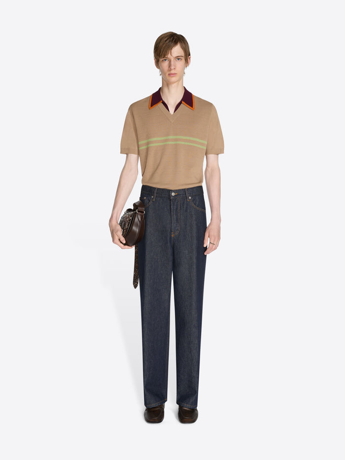 Person wearing a beige polo shirt with colorful collar and dark jeans on a white background - Dries Van Noten