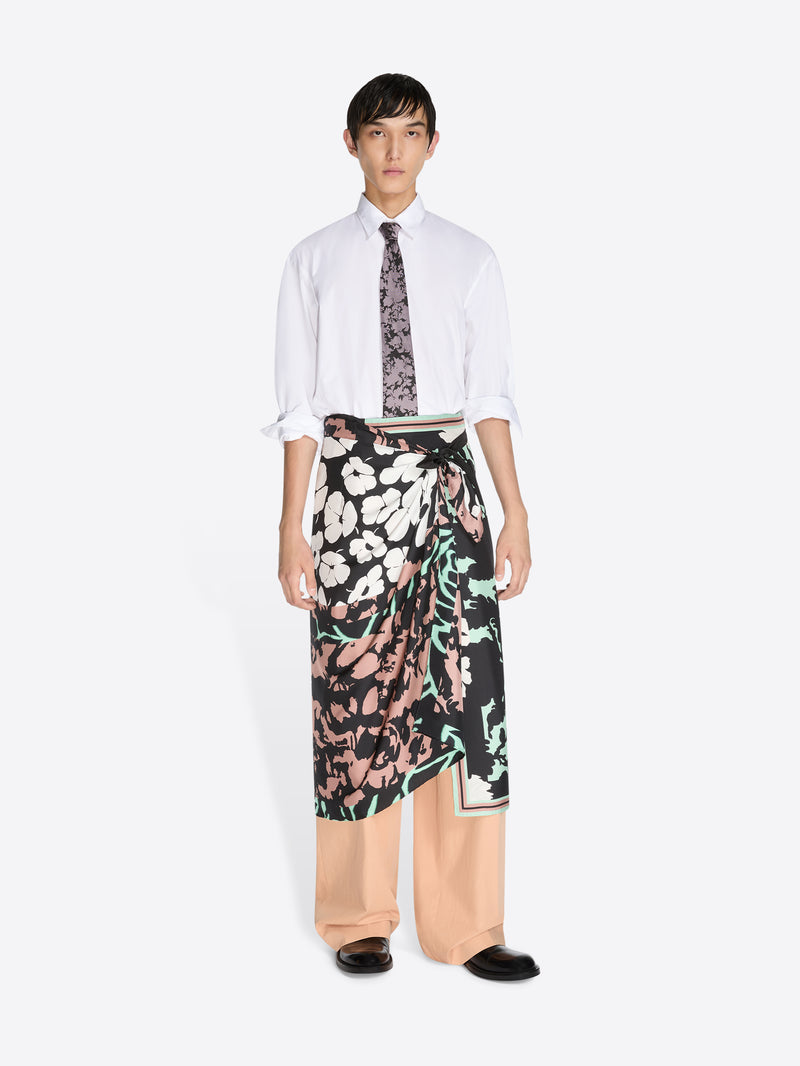 Person wearing a white shirt, patterned tie, and floral skirt on a white background