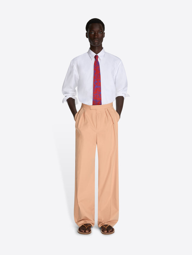 Person wearing a white shirt, red tie, and beige pants on a white background