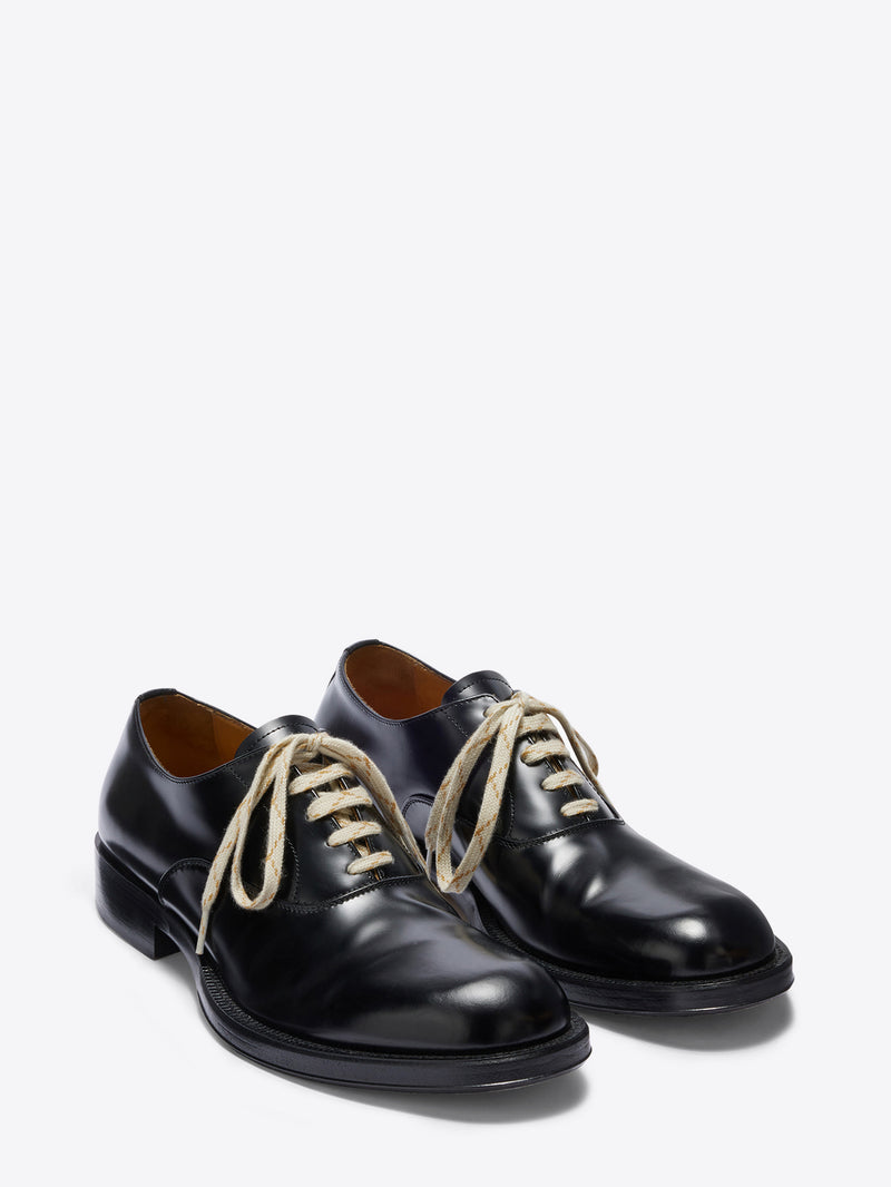 Pair of black leather shoes with white laces on a white background