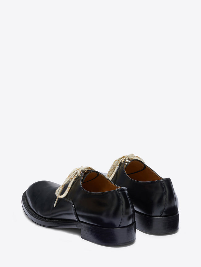 Pair of black leather shoes with white laces on a white background