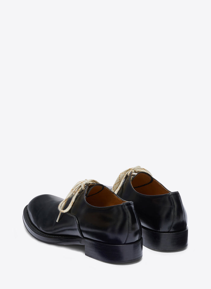 Pair of black leather shoes with white laces on a white background
