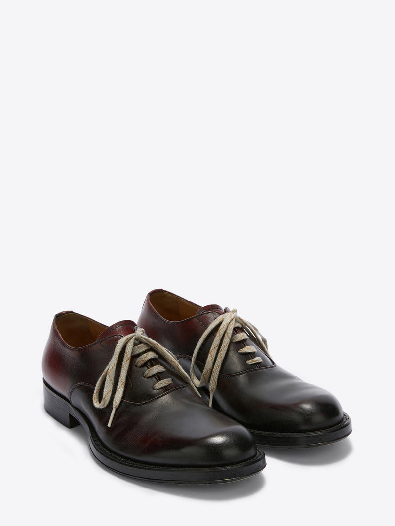 Pair of brown leather shoes with white laces on a white background