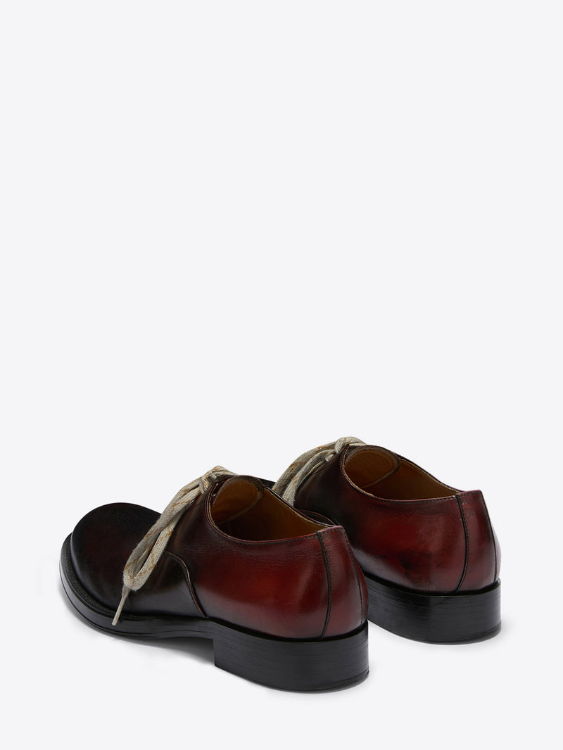 Pair of brown leather shoes with black soles on a white background