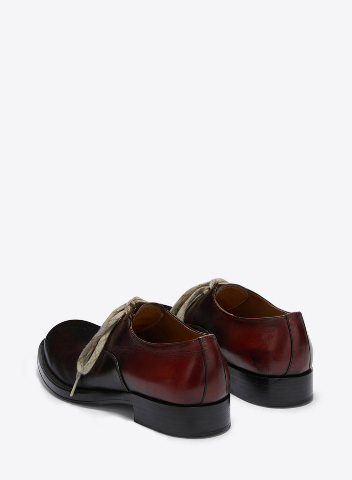 Pair of brown leather shoes with black soles on a white background