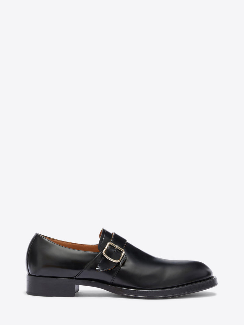 Black leather dress shoe with a buckle on a white background