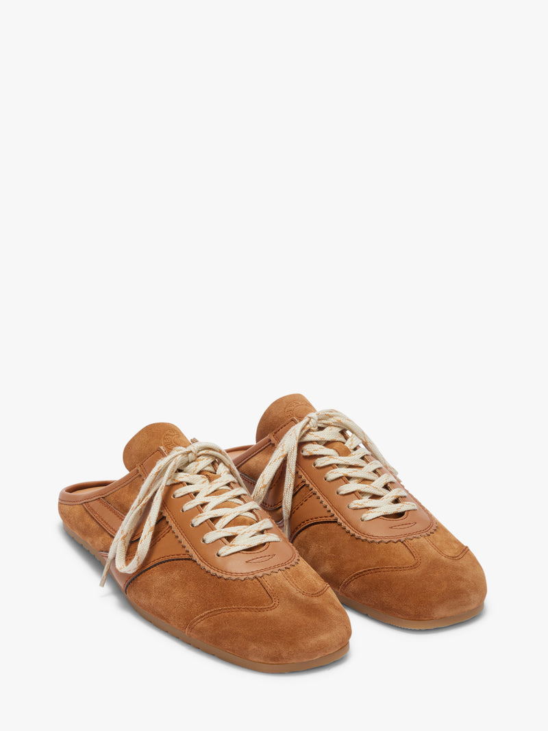 Pair of brown suede shoes with white laces on a white background