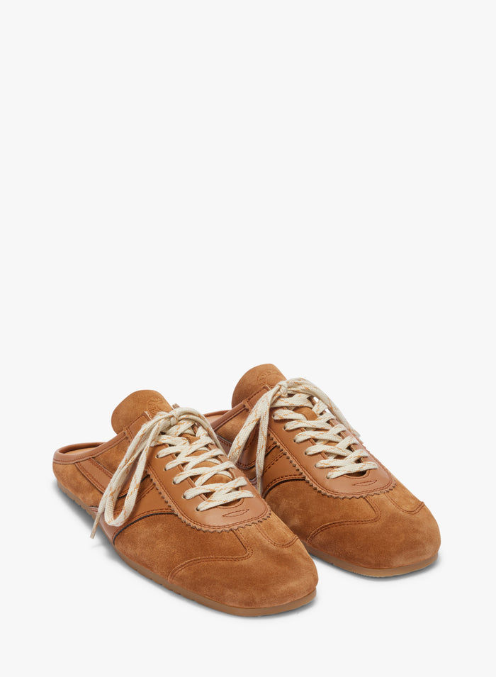 Pair of brown suede shoes with white laces on a white background