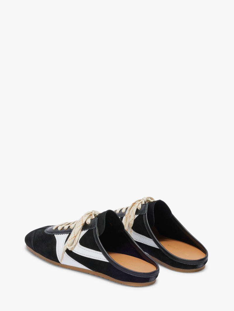 Black and white slip-on shoes with tan soles on a white background