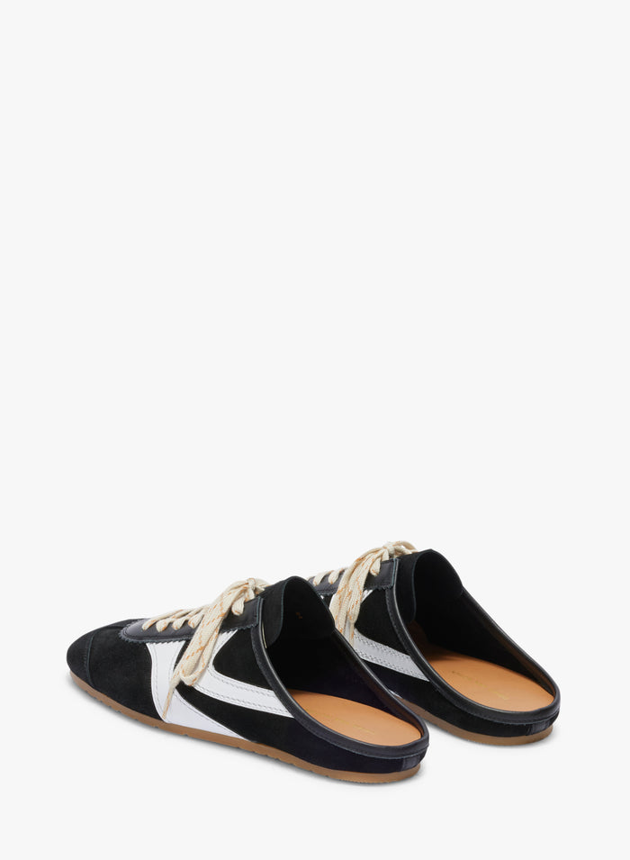 Black and white slip-on shoes with tan soles on a white background