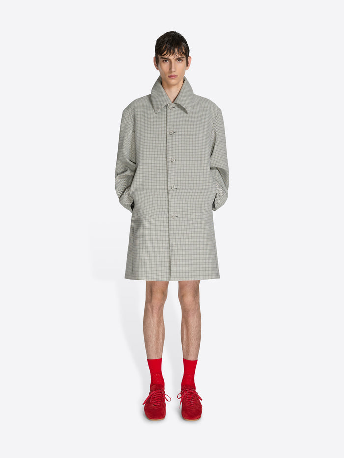 Person wearing a light gray checkered coat with red shoes on a white background - Dries Van Noten
