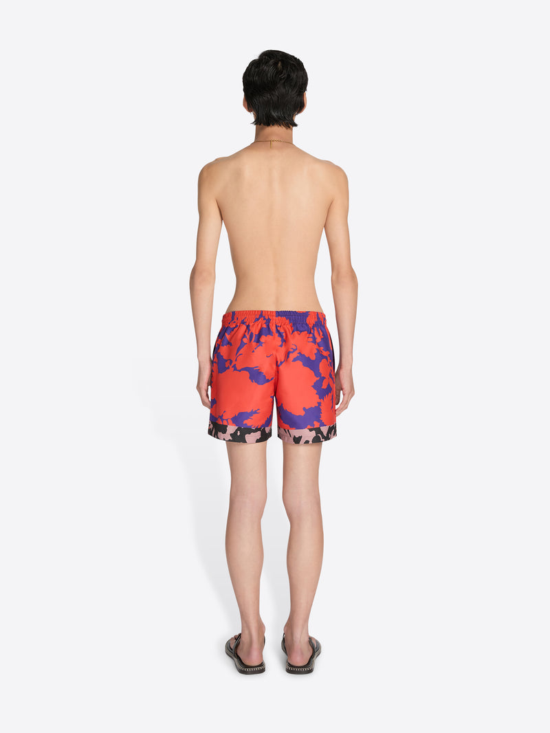 Person wearing colorful swim shorts on a white background
