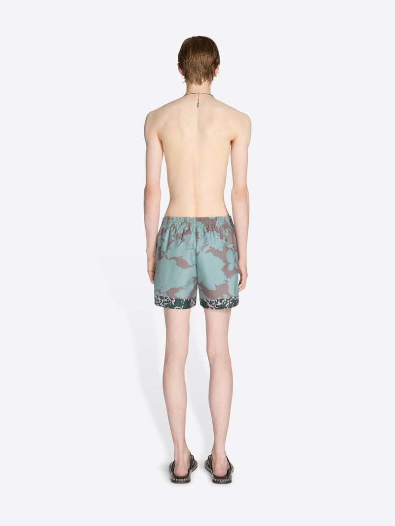 Person wearing camouflage swim shorts on a white background