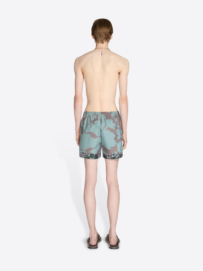 Person wearing camouflage swim shorts on a white background