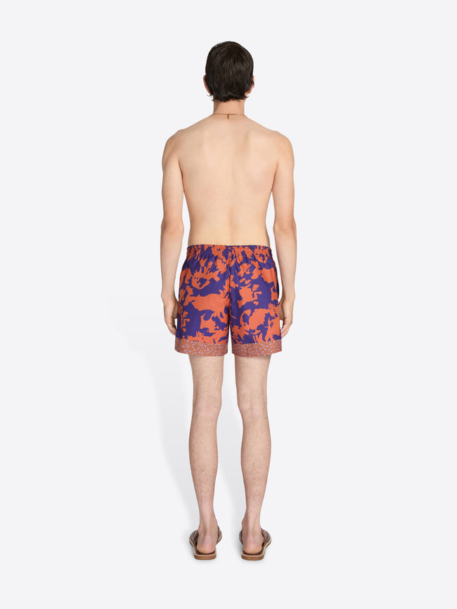 Person wearing colorful swim shorts on a white background