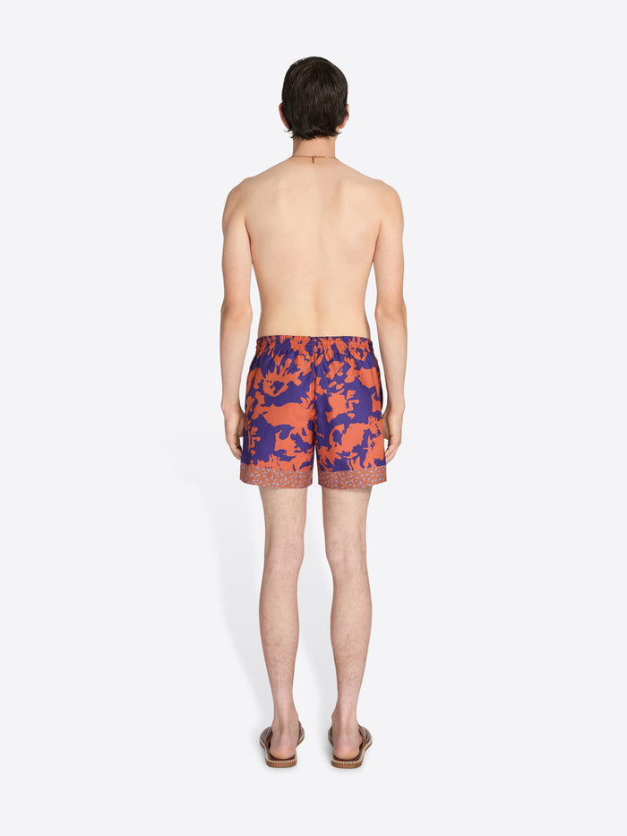 Person wearing colorful swim shorts on a white background