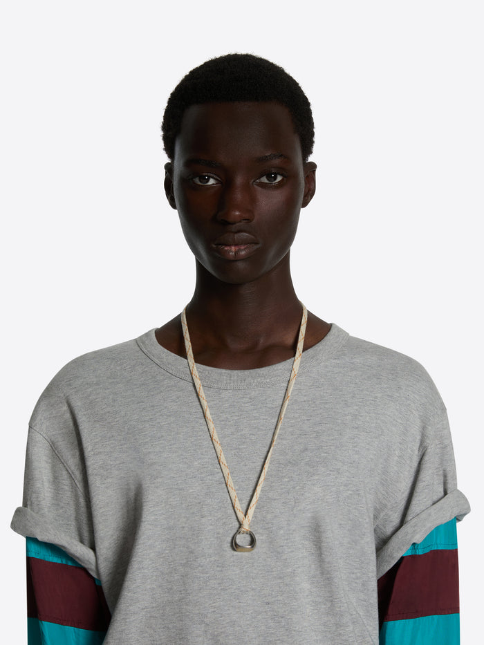 Person wearing a long necklace against a plain background