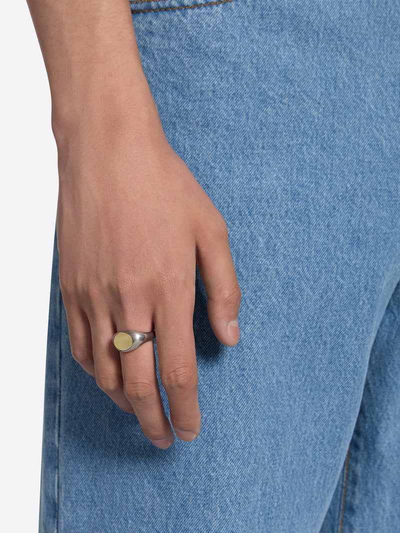 Hand wearing a ring with blue denim fabric in the background