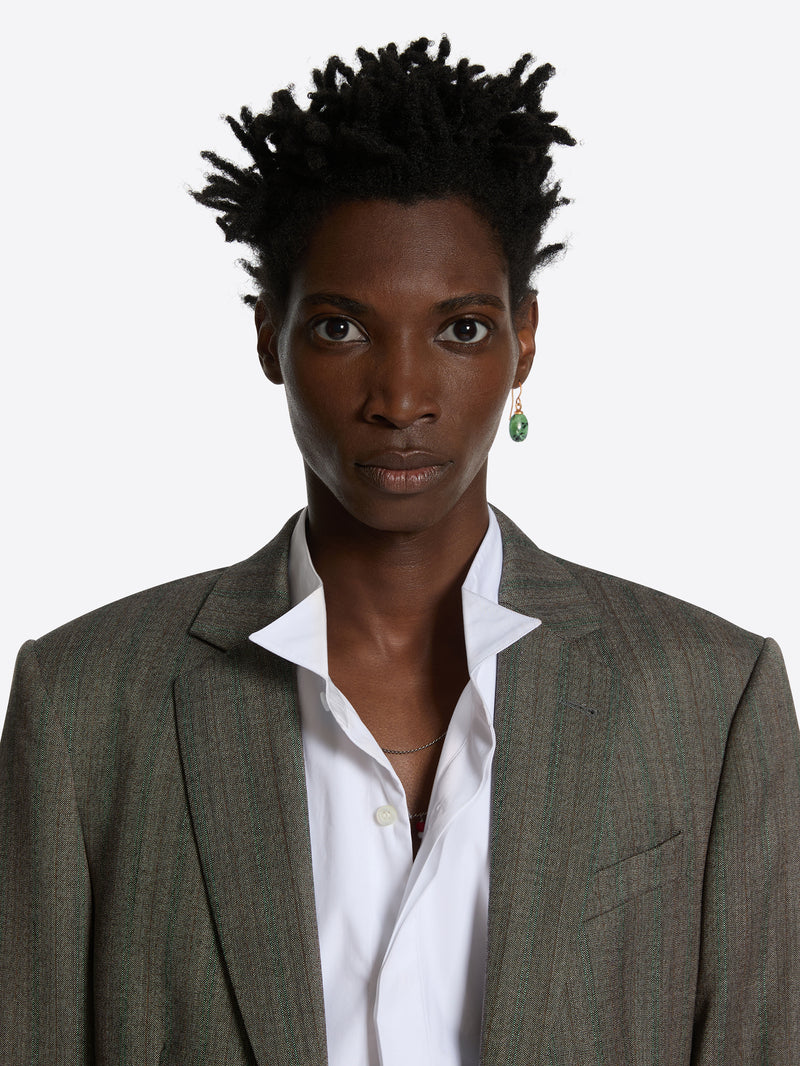 Person wearing a gray blazer over a white shirt with a plain background